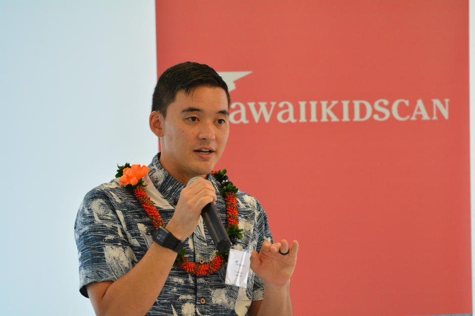 David Miyashiro, wearing a Hawaiian shirt and red flowered lei, speaks at the Educational Equity Symposium in September 2017