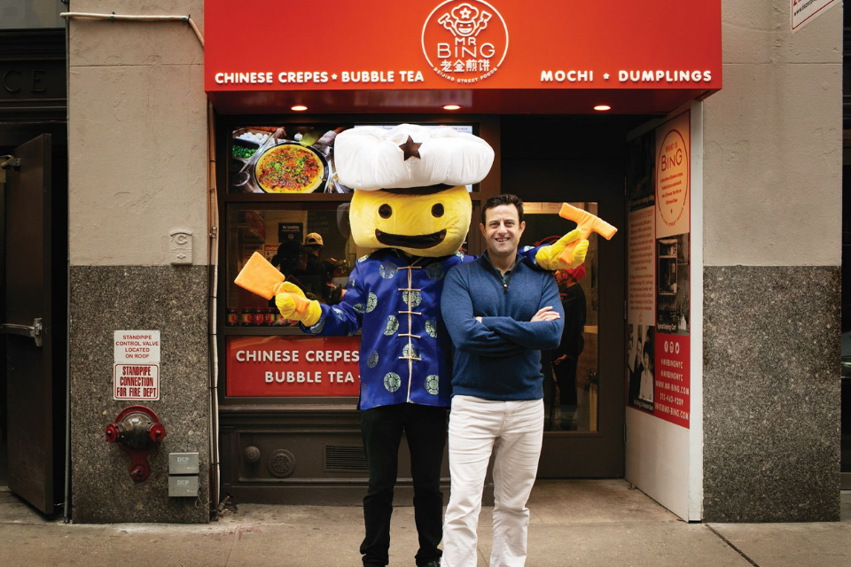 Brian Goldberg stands next to Mr. Bing, the store mascot, a yellow character costume with blue clothes and a white hat with a star
