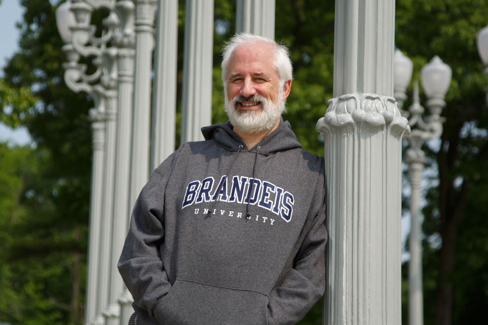 Lewis Brooks wearing a Brandeis sweatshirt, standing in front of the Light of Reason