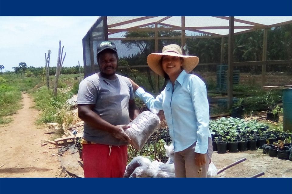 Carol Lue (left) and a man stand in front of a greenhouse
