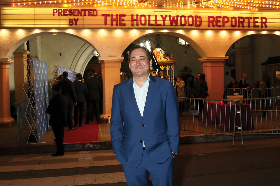Scott  Feinberg smiling and standing in front of a marquee that reads "The Hollywood Reporter"