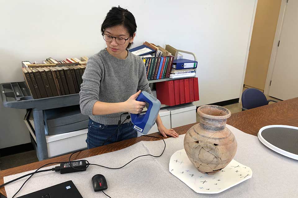 Helen Wong holding a 3-D scanner used for scanning artifacts