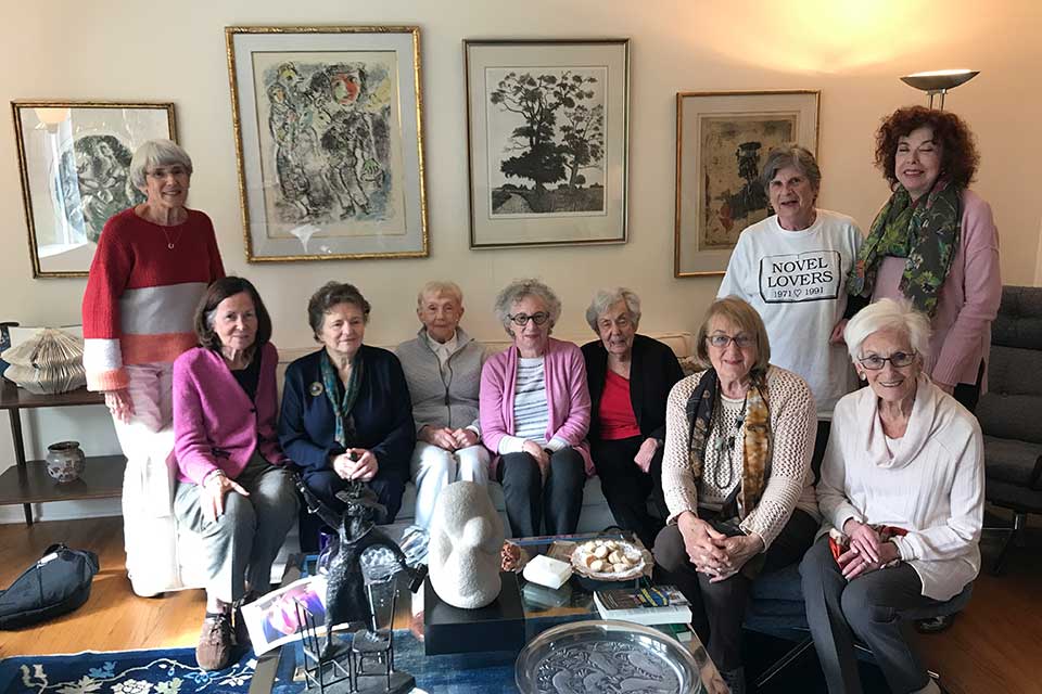 A group of alumnae members of a book club sitting together in a living room.