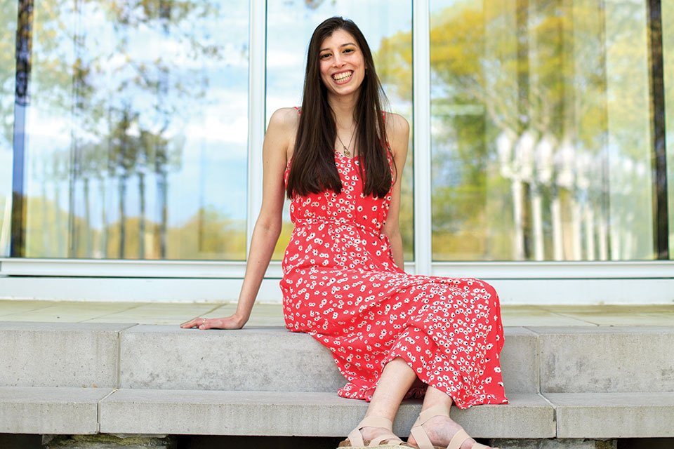 Lizzy Topper smiling, seated in front of  the Rose Art Museum