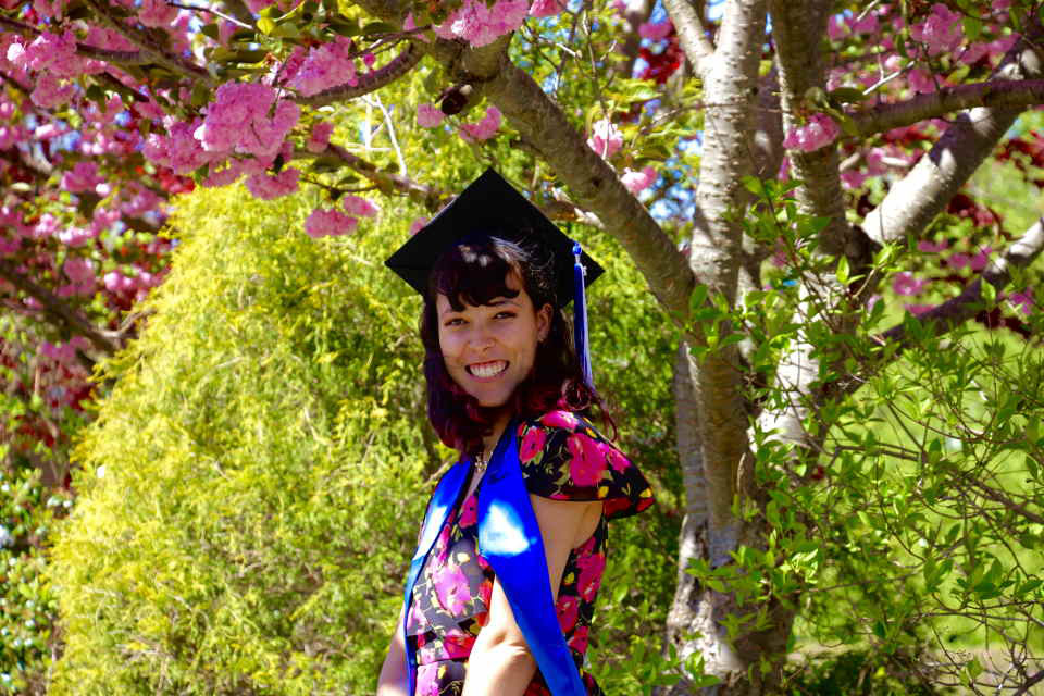 Aviva Davis, outside smiling in a graduation cap.