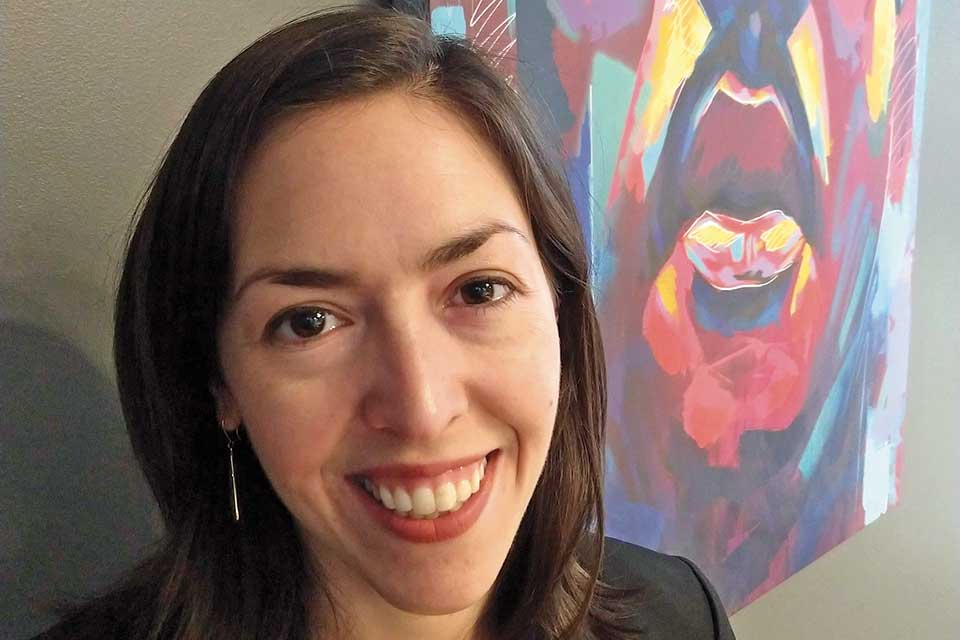 Laura Wolf smiling in front of a painting of Martin Luther Ling Jr. 