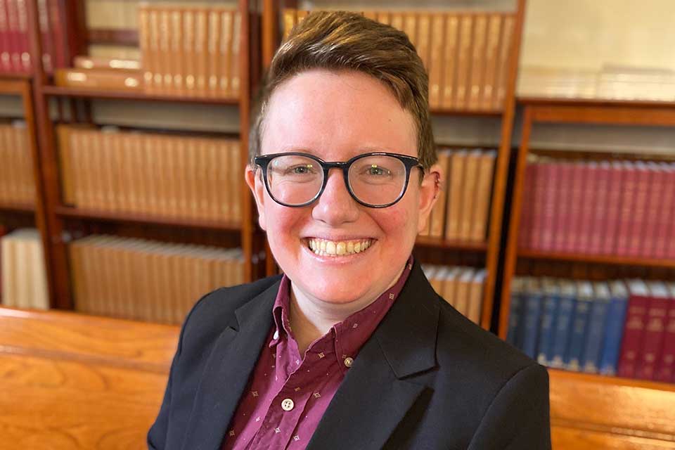 Lily Solochek smiling with a bookcase in the background