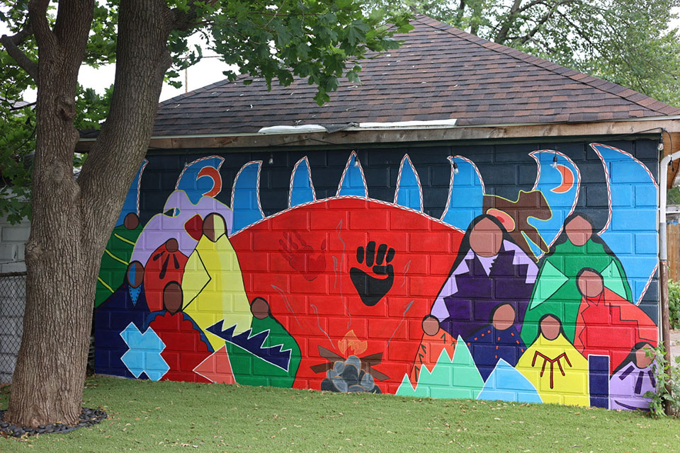 A mural of Wampanoag people painted on the side of a building.